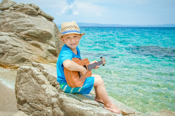 happy child playing guitar by the sea greece on nature background