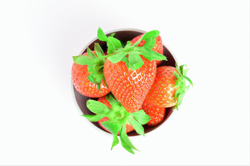 Strawberries in a bowl, presented on a white background and zenith  view.
