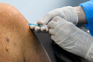 Close up of the hands of a healthcare worker who vaccinates an elderly person with a coronavirus...