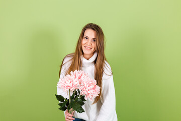 Pretty european woman in casual white sweater isolated on green background romantic look holding bouquet of pink flowers with smile