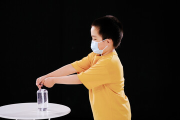 Little boys with masks use hand sanitizer