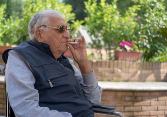 Senior man smoking cigarette in the garden