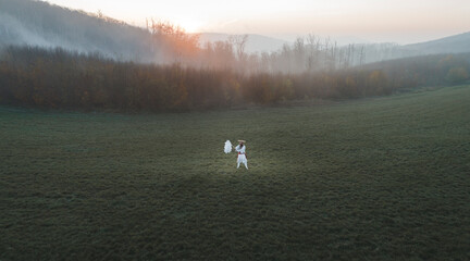 Naklejka na ściany i meble Man is standing in traditional japanese shugendo outfit on green meadow in heavy fog