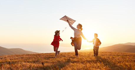 Happy family  mother and kids  launch  kite on nature at sunset