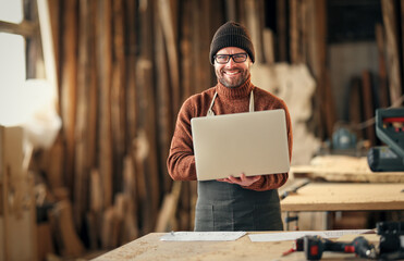 Craftsman working with laptop and papers in workshop