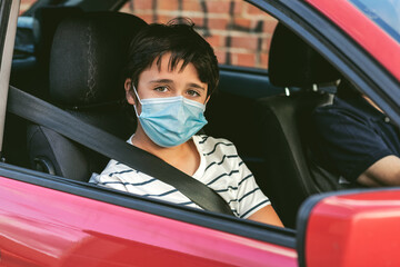 kid with protective surgical mask riding in a car