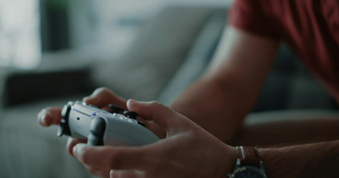 Close up hands man playing video games on modern next gen console with gamepad at home. Remote, television, entertainment. Slow motion