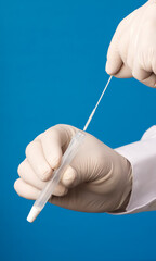 Doctor hands with hyssop and transport vial, process for coronavirus analysis, blue background.