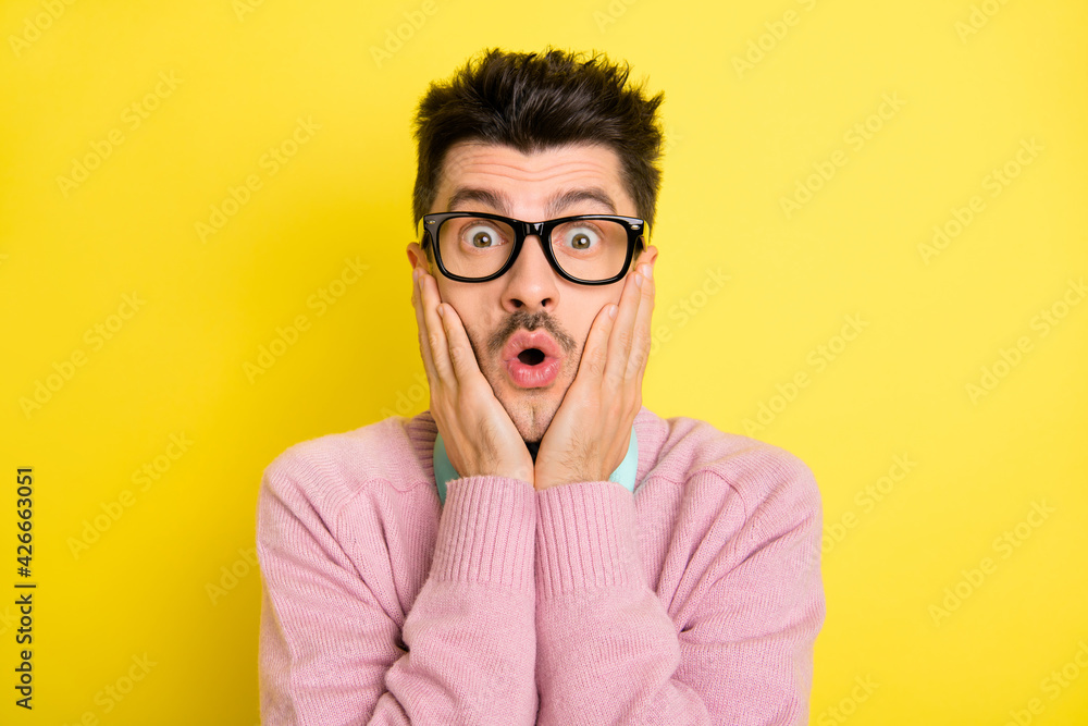 Wall mural Photo of young man amazed shocked surprised news fake novelty hands touch cheeks isolated over yellow color background