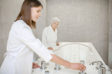 Specialist in spa salon getting the bath for hydromassage ready