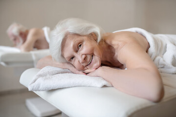 Fototapeta na wymiar Senior woman lying on na couch in a spa salon and enjoying