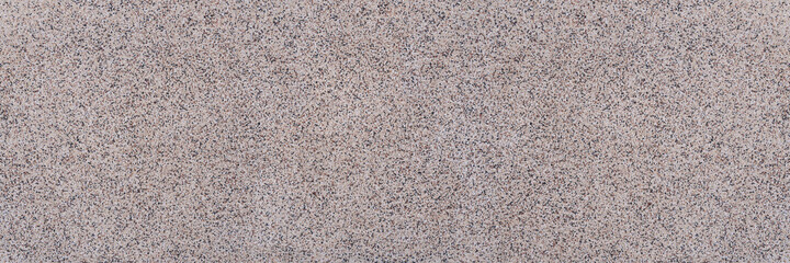 Panorama Nahaufnahme einer Platte mit abstrakter körniger Textur aus kleinen Steinen in beige, braun, weiß und schwarz 