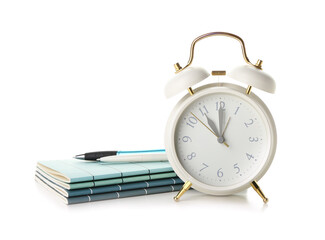 Alarm clock, notebooks and pens on white background