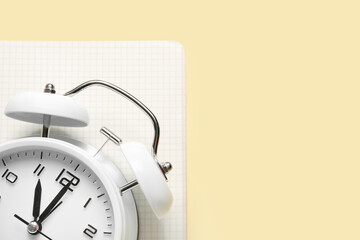 Alarm clock and notebook on color background, closeup