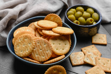 Bowl with crackers and olives on wooden background