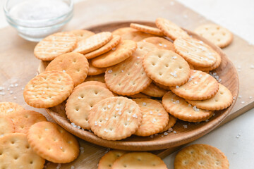 Plate of tasty crackers on wooden background