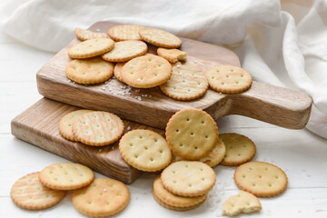 Board with crackers on light background