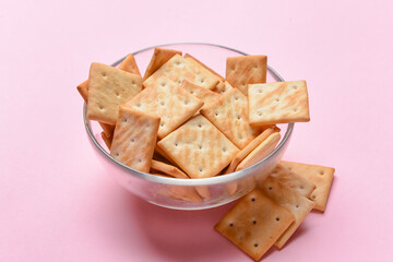 Bowl of crackers on color background