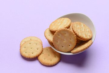 Bowl of crackers on color background