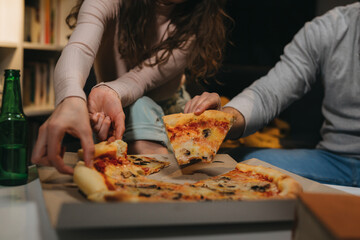 romantic couple eating pizza at home. moody evening atmosphere