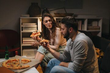 romantic couple eating pizza at home. moody evening atmosphere