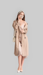 Fashionable young woman wearing mask on grey background