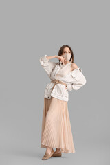 Fashionable young woman wearing mask on grey background