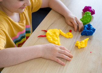 A preschool girl makes a duck from plasticine. Homemade plastiline. Activities for children in quarantine. Girl sculpts from plasticine at home on isolation. Coronavirus 2021.