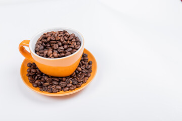 close-up of a orange ceramic cup with white inside, on a plate with coffee beans on a white surface, horizontal photo, with space to write