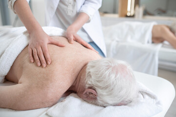 Fototapeta na wymiar Massage therapist working with an elderly male patient