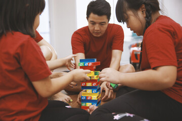 Young family having fun with playing colorful bricks together at home
