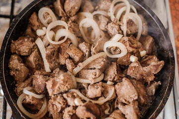 Fried veal liver with onions in a pan. Braised cow and pork liver
