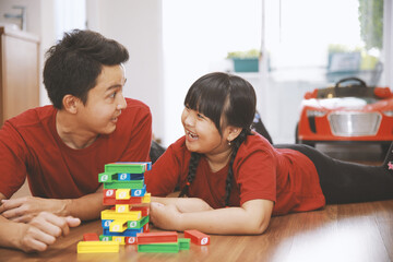 Father and daughter playing colorful bricks together at home