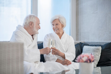 Senior couple in white robes celebrating and looking happy