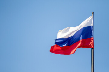 Fototapeta na wymiar Russian flag waving against the blue sky