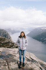 A pretty girl stands on top of Mount Preikestolen (Pulpit Rock) in Norway