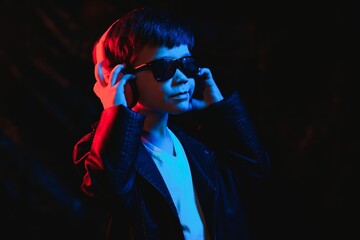 teen boy listening to music with headphones, neon light trending portrait. Looks at the camera