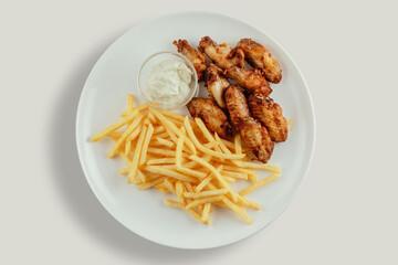 Chicken wings with french fries and garlic mayonnaise and sweet and sour sauce.