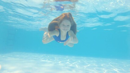 Young girl swimming underwater in the Swimming Pool. Summertime leisure activities