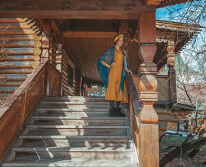 Russian beauty closeup is sitting on the stairs of wooden house in the village