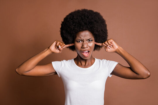 Portrait of furious unsatisfied dark skin lady open mouth grimace fingers close ears isolated on brown color background