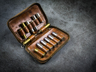 Small zippered leather bag to store bullet, placed on a black cement floor.