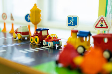 Obraz premium toy pedestrian crossing. multicolored little cars stand on the play road next to traffic lights, traffic signs