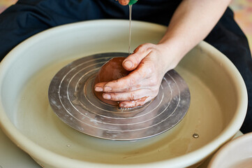 Hands of a master potter, getting started with clay. Handicraft production in the workshop.