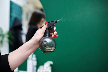 Close-up picture of hairdresser's tools in female hands isolated on green background. Small black...