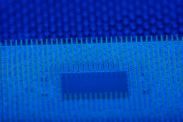Close-up of a part of a microprocessor in soft focus under high magnification. Details of a computer component under a microscope in tech blue light.