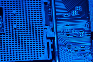 High tech dark background with elements of a computer motherboard in soft focus under high magnification. A slot for a processor with a lever for locking onto the home computer board.