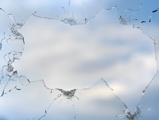 Broken window glass on a background of blue sky