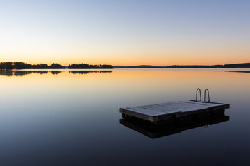 panorama of a wooden raft on calm lake water at sunrise or sunset