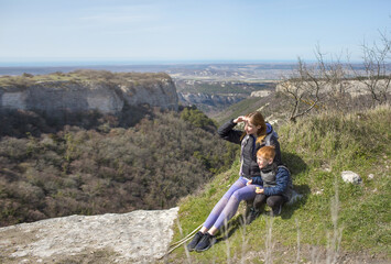 Obraz premium family of tourists a woman and a child sit on the top of the mountain